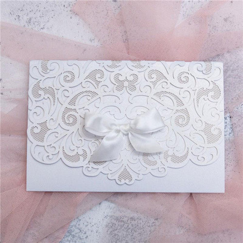 white laser cut wedding invitation with bow