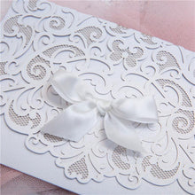 white laser cut wedding invitation with bow